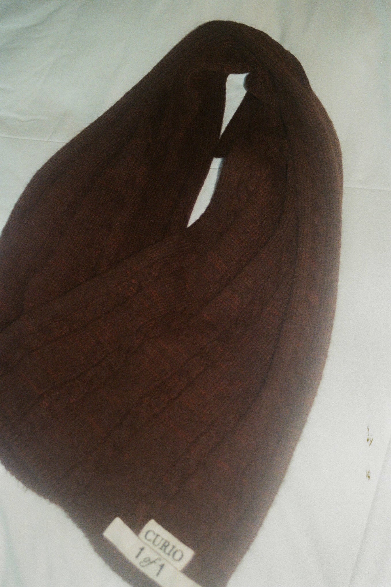 Brown knitted scarf with a label on a white background