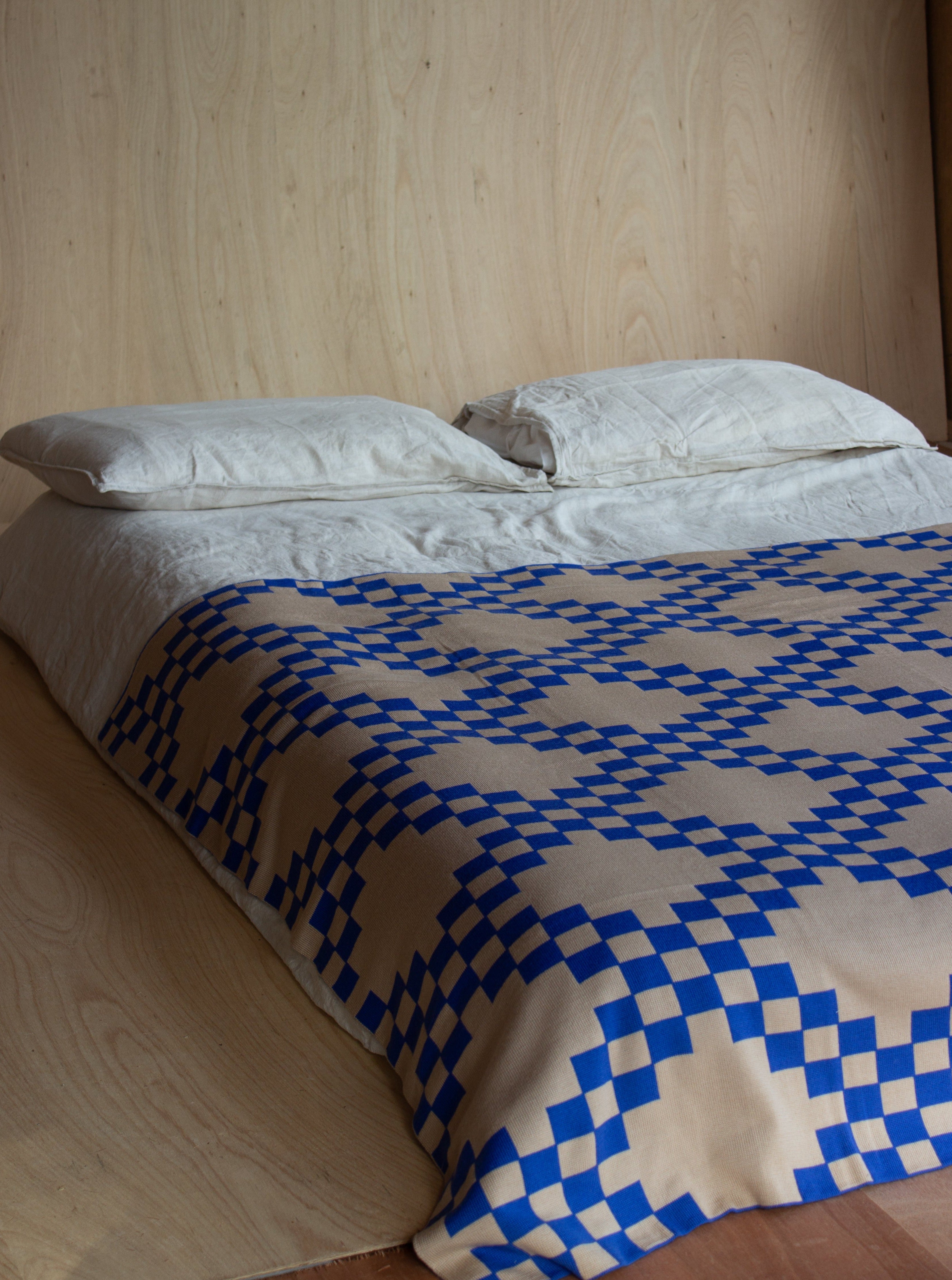 The WAVE blanket in CURIO’s signature balanced chain check is knitted from the finest Merino wool yarn (21 microns) for unparalleled softness and durability. Blanket edges are finished by hand, and the CURIO label affixed to each blanket is embroidered in Central Victoria from Australian cotton and attached by hand.. The blanket is Bright blue with checked pattern throughout and a mushroom base colour